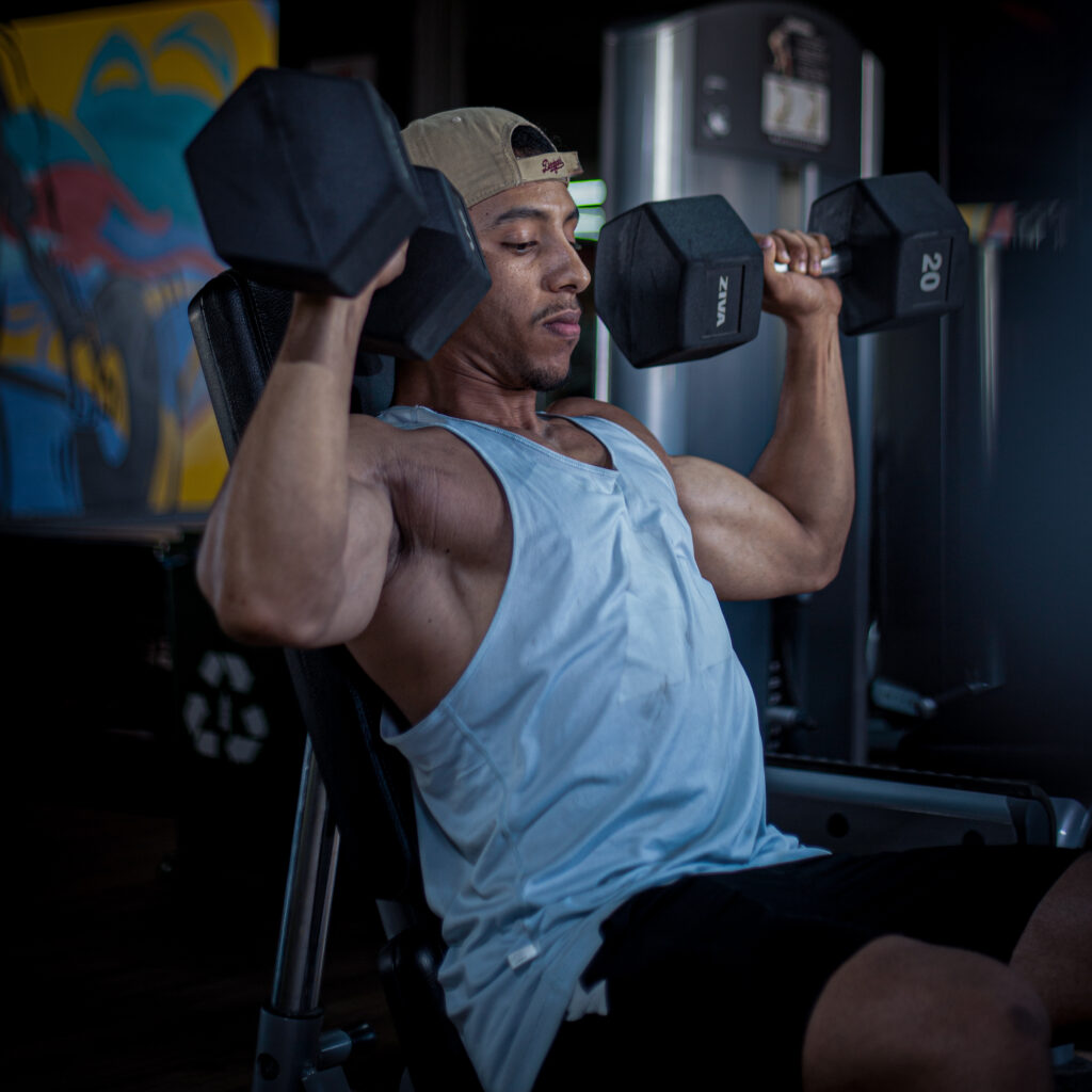 Strength Training for Women Beginners: The Complete Guide 1 Female beginner lifting dumbbells in shoulder press inside a gym.